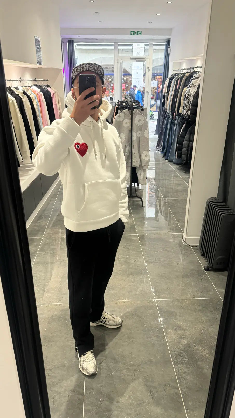 Selfie-look reflétant les détails du cœur rouge brodé en relief sur le pull à capuche ADJ blanc.