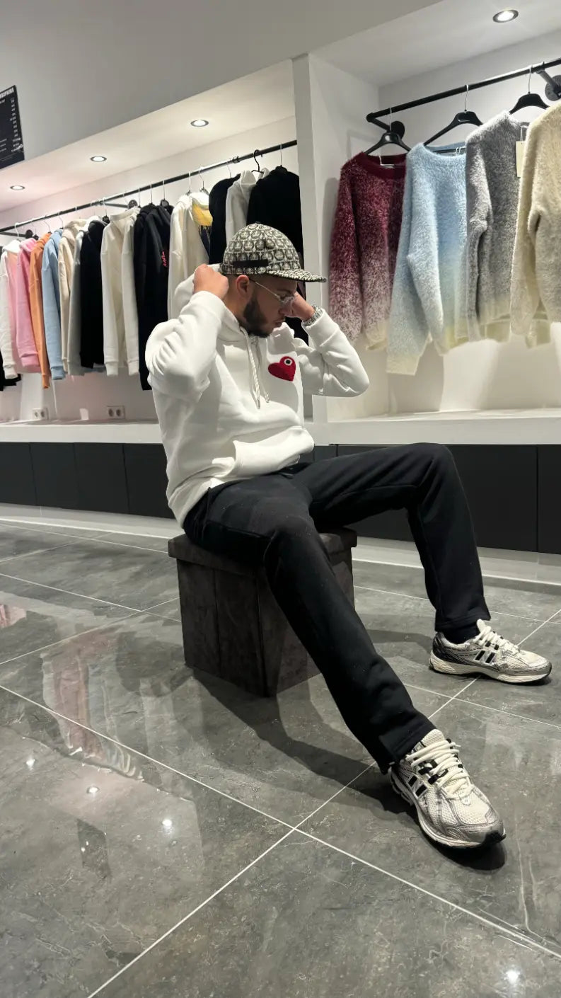 Modèle assis avec le pull ADJ blanc au cœur rouge pour un rendu décontracté et une attitude street.