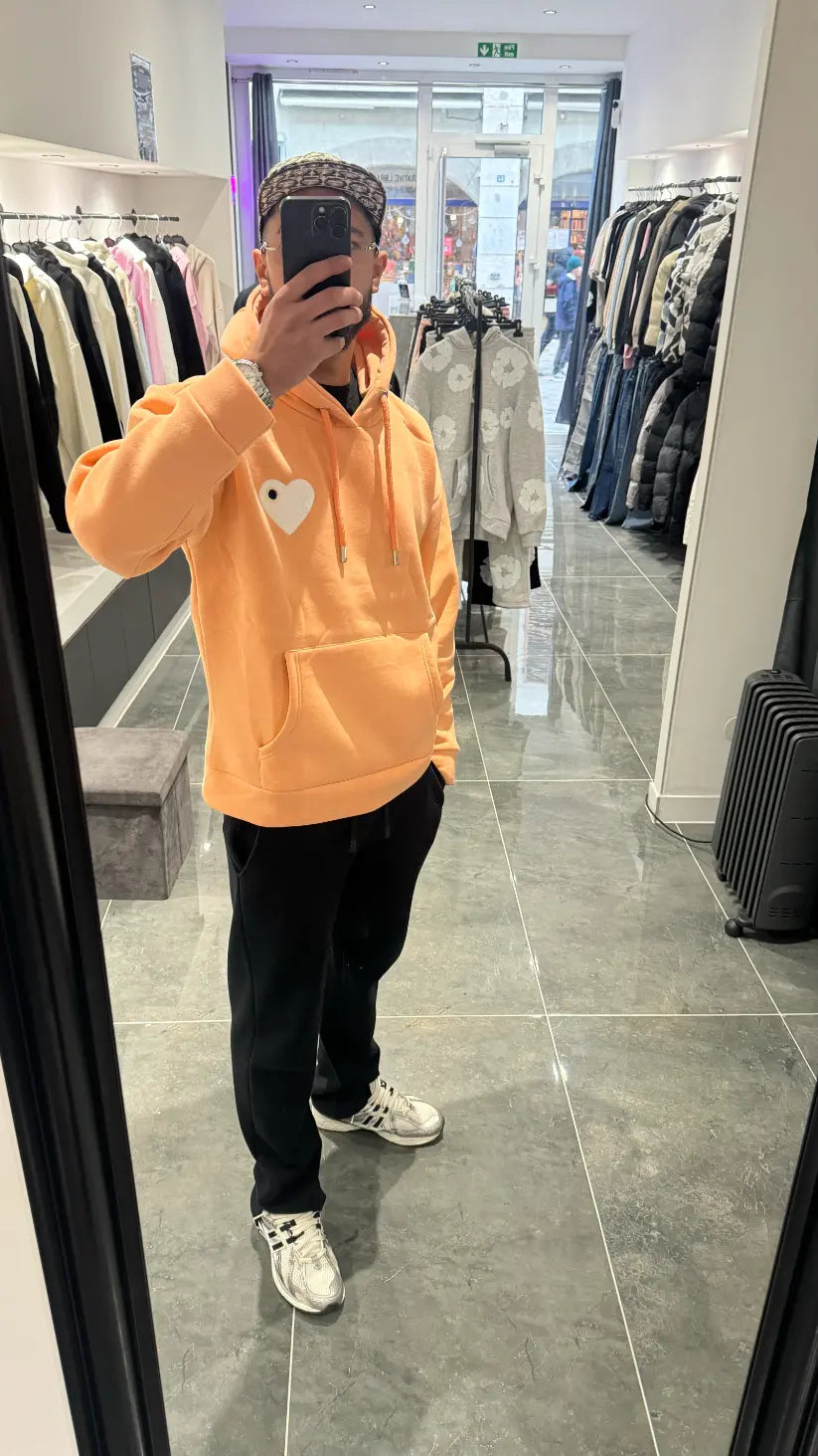 Selfie-look du pull à capuche ADJ orange clair montrant le reflet et la texture du logo en éponge.
