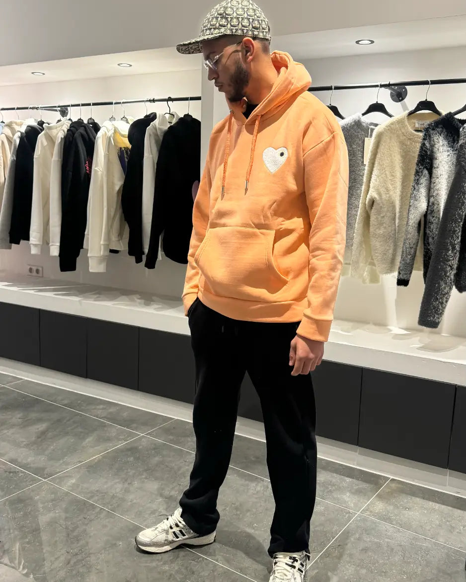 Modèle debout présentant la shape et le tombé du pull ADJ orange clair en coupe classique.