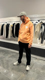 Modèle debout présentant la shape et le tombé du pull ADJ orange clair en coupe classique.