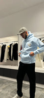 Modèle debout exposant la shape complète et la coupe classique du pull ADJ bleu clair en lumière naturelle.