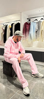 Modèle assis portant le zipper hoodie ADJ rose avec son cœur blanc brodé pour un look décontracté.