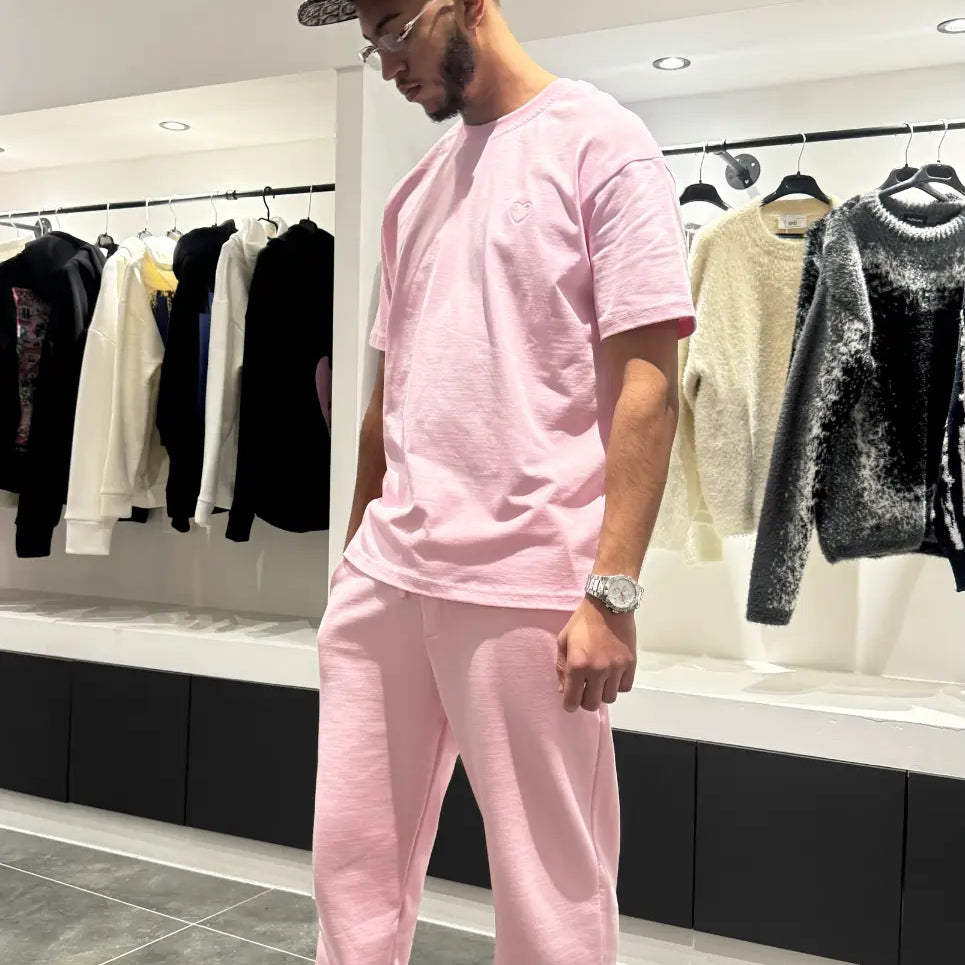 Vue d'ensemble du modèle debout montrant la coupe regular fit et le tombé impeccable du t-shirt ADJ rose.
