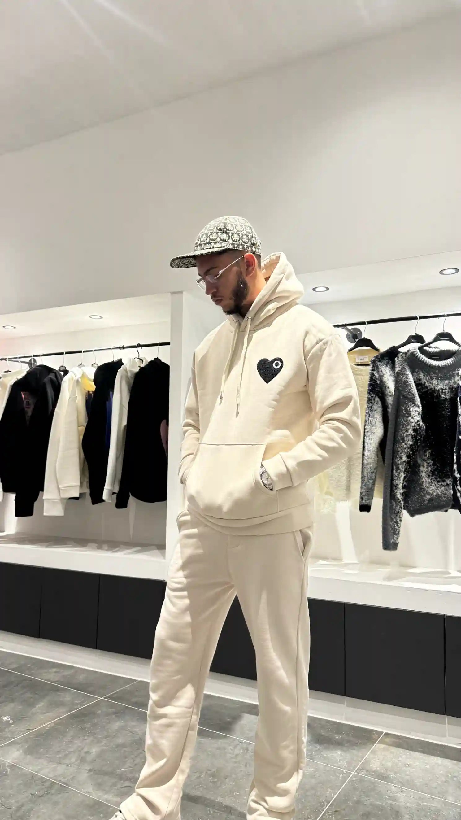 Vue d'ensemble du modèle debout avec le pull à capuche ADJ beige pour un outfit urbain structuré.