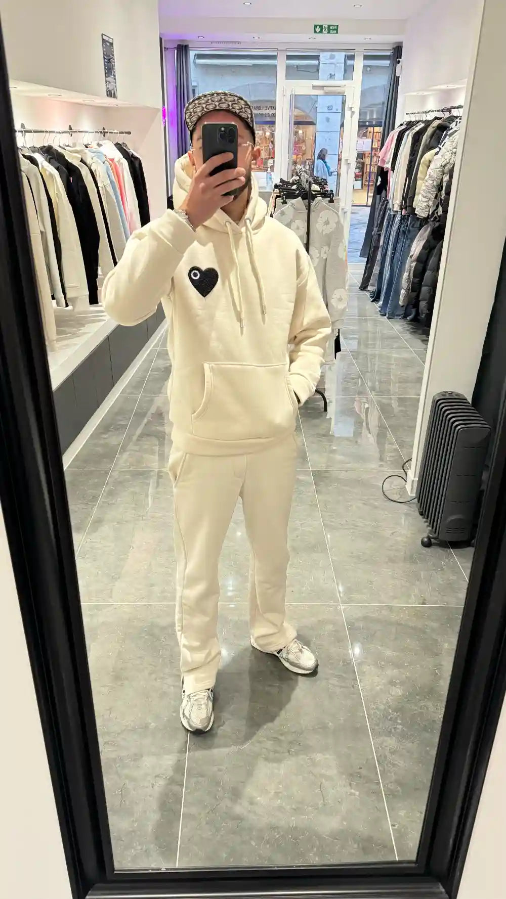 Selfie-look du pull ADJ beige devant le miroir mettant en avant le relief du cœur noir brodé.