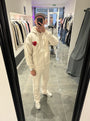Selfie-look du gilet à capuche ADJ beige mettant en relief le logo cœur rouge en éponge.
