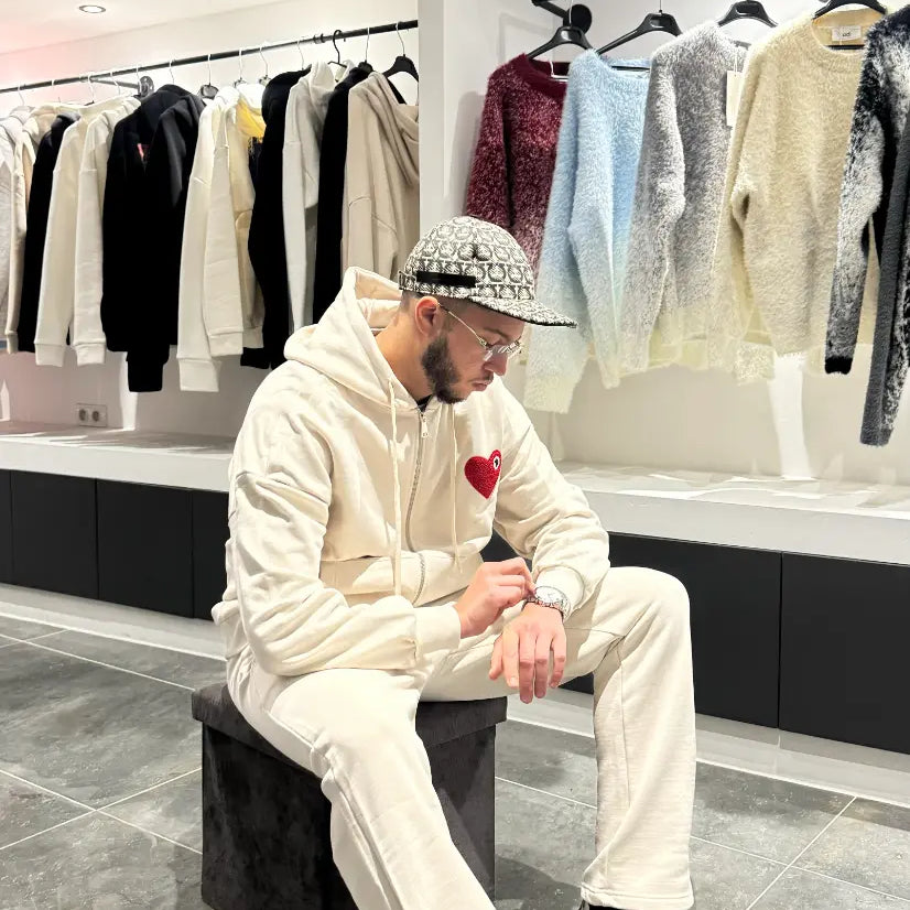 Pose décontractée du modèle assis portant le gilet ADJ beige avec son cœur rouge brodé.