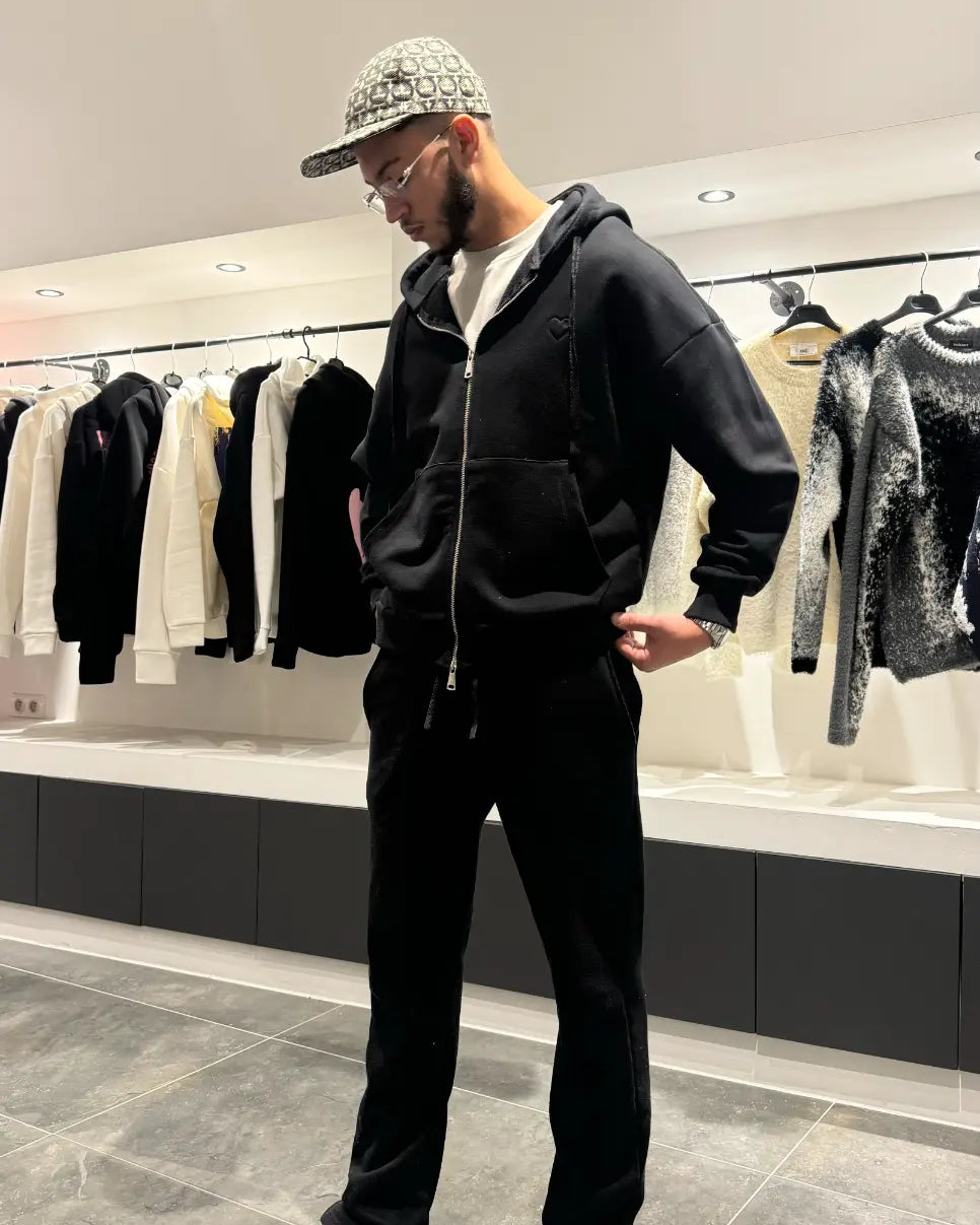 Modèle debout mettant en avant le style urbain et la finition premium du gilet à capuche noir ADJ.