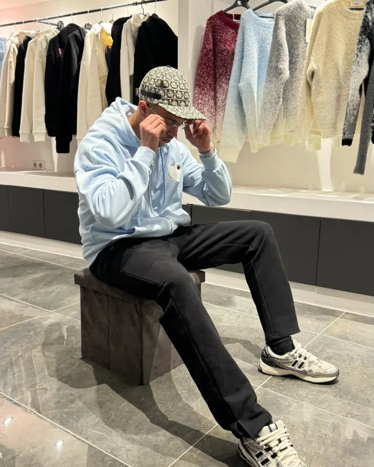 Pose décontractée du modèle assis avec le gilet bleu clair ADJ pour un look urbain et frais.