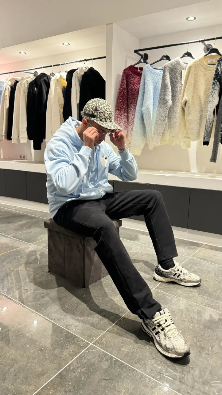 Pose décontractée du modèle assis avec le gilet bleu clair ADJ pour un look urbain et frais.