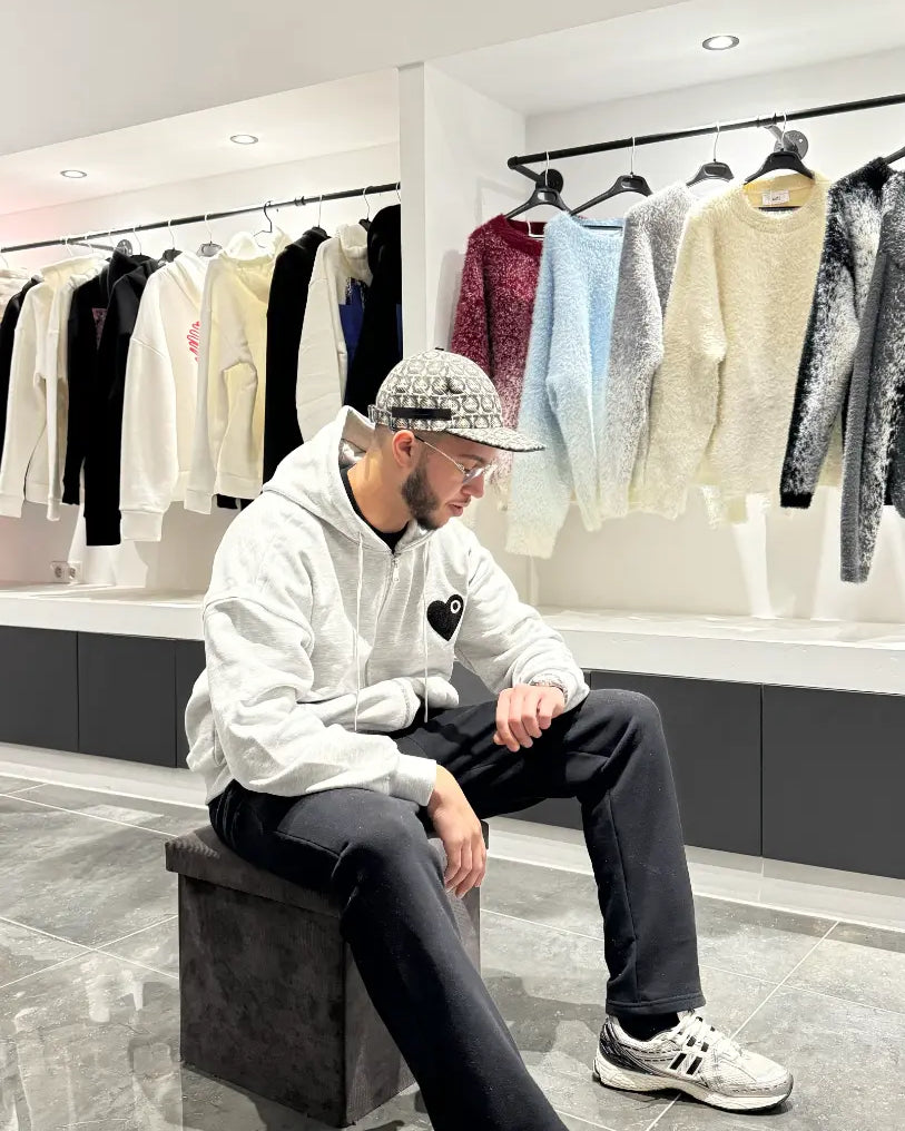 Modèle assis avec le gilet gris ADJ mettant en valeur le confort et le logo cœur noir.
