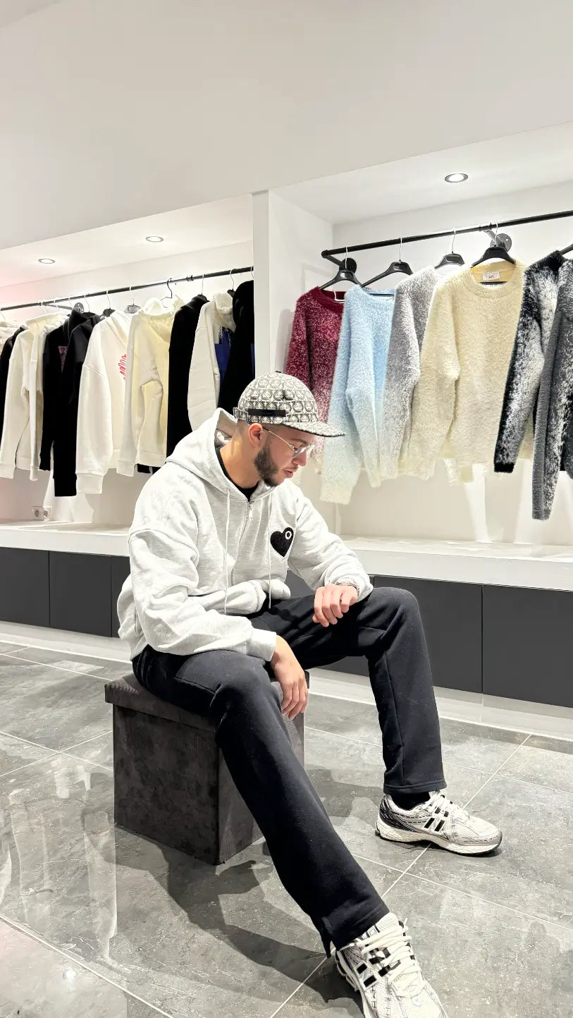Modèle assis avec le gilet gris ADJ mettant en valeur le confort et le logo cœur noir.