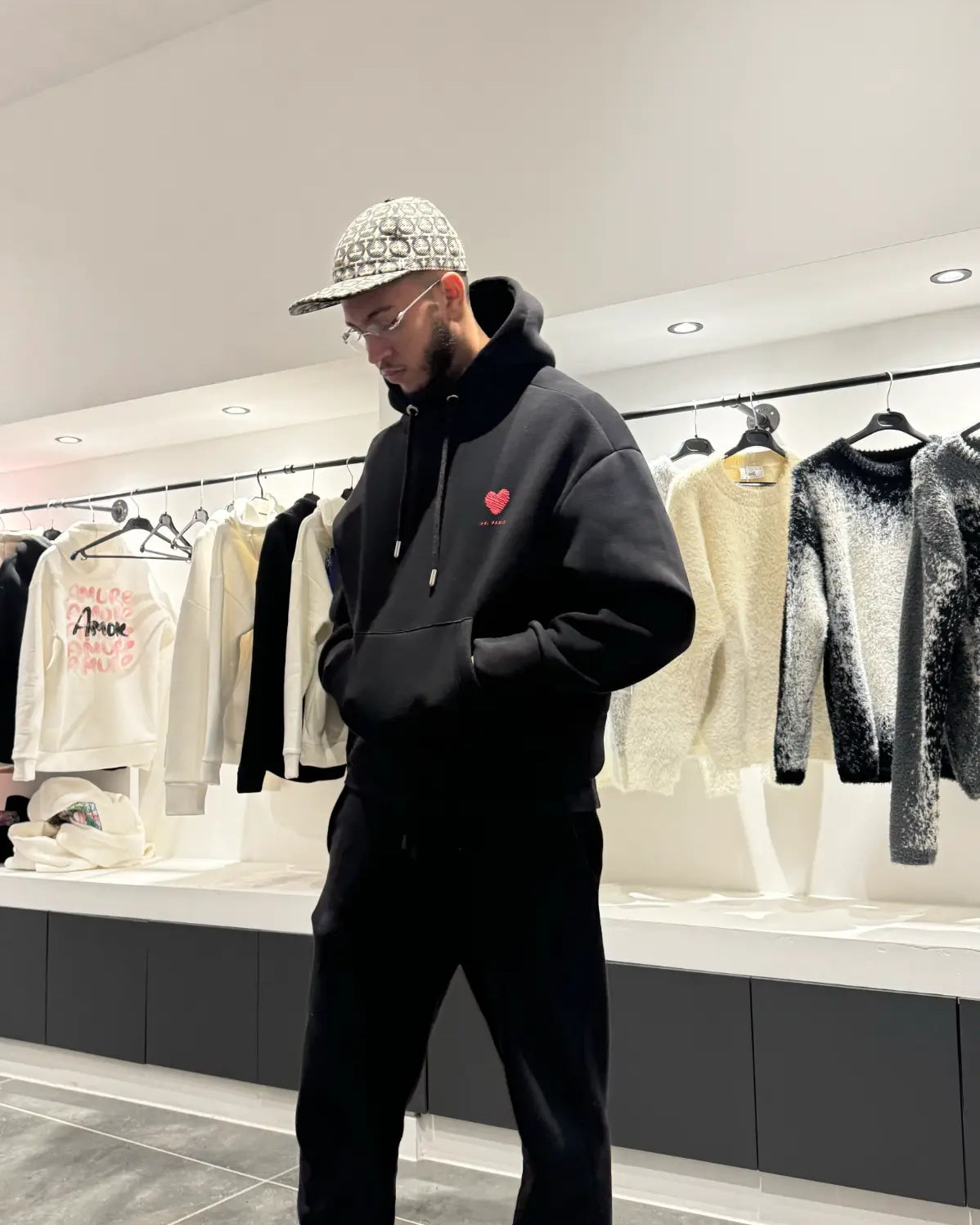 Silhouette avec le pull ADJ noir montrant le volume oversize et le contraste des prints rouges dans le reflet.