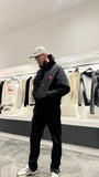 Silhouette avec le pull ADJ noir montrant le volume oversize et le contraste des prints rouges dans le reflet.