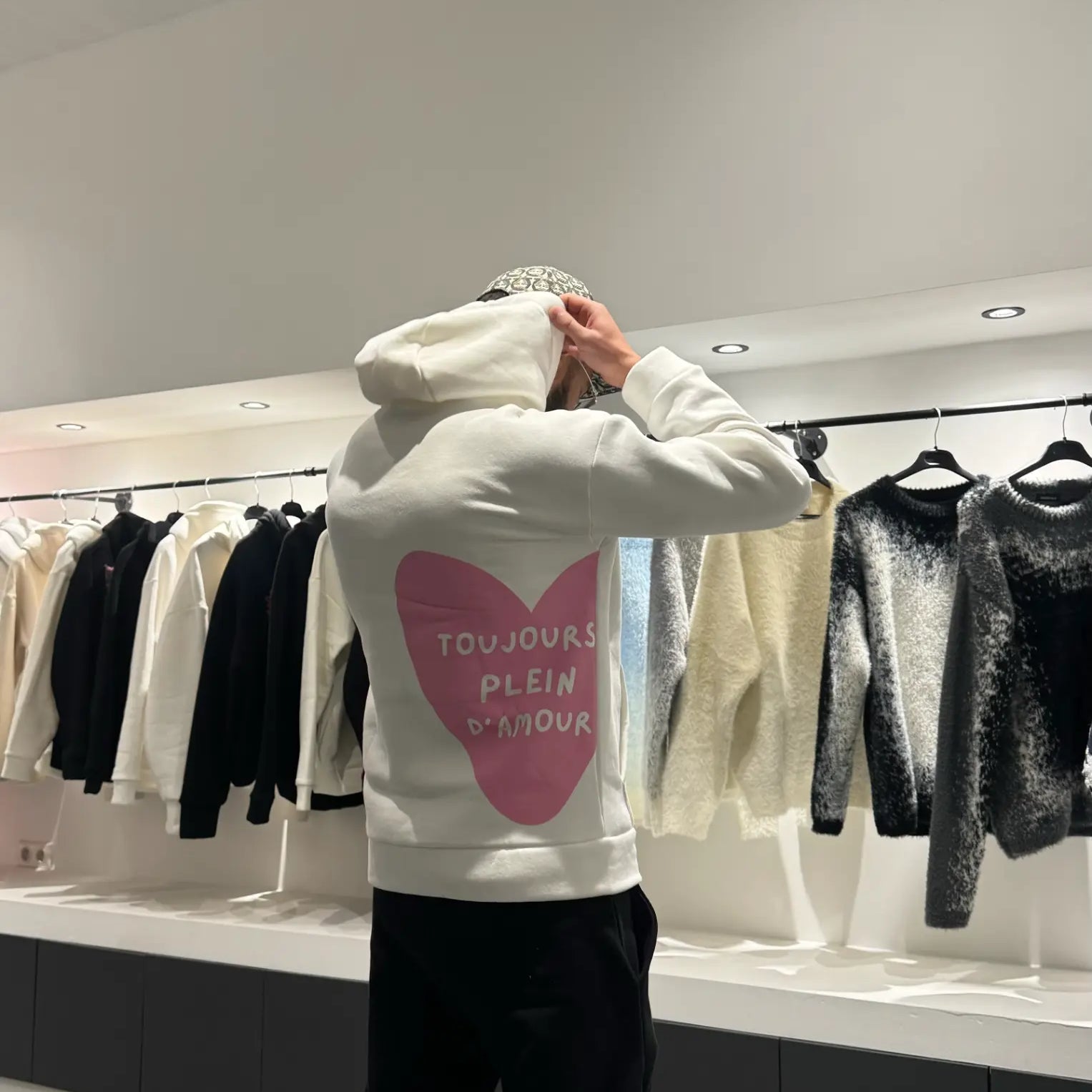 Focus sur le message "toujours plein d'amour" écrit en rose au dos du pull blanc ADJ.