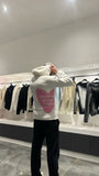 Focus sur le message "toujours plein d'amour" écrit en rose au dos du pull blanc ADJ.