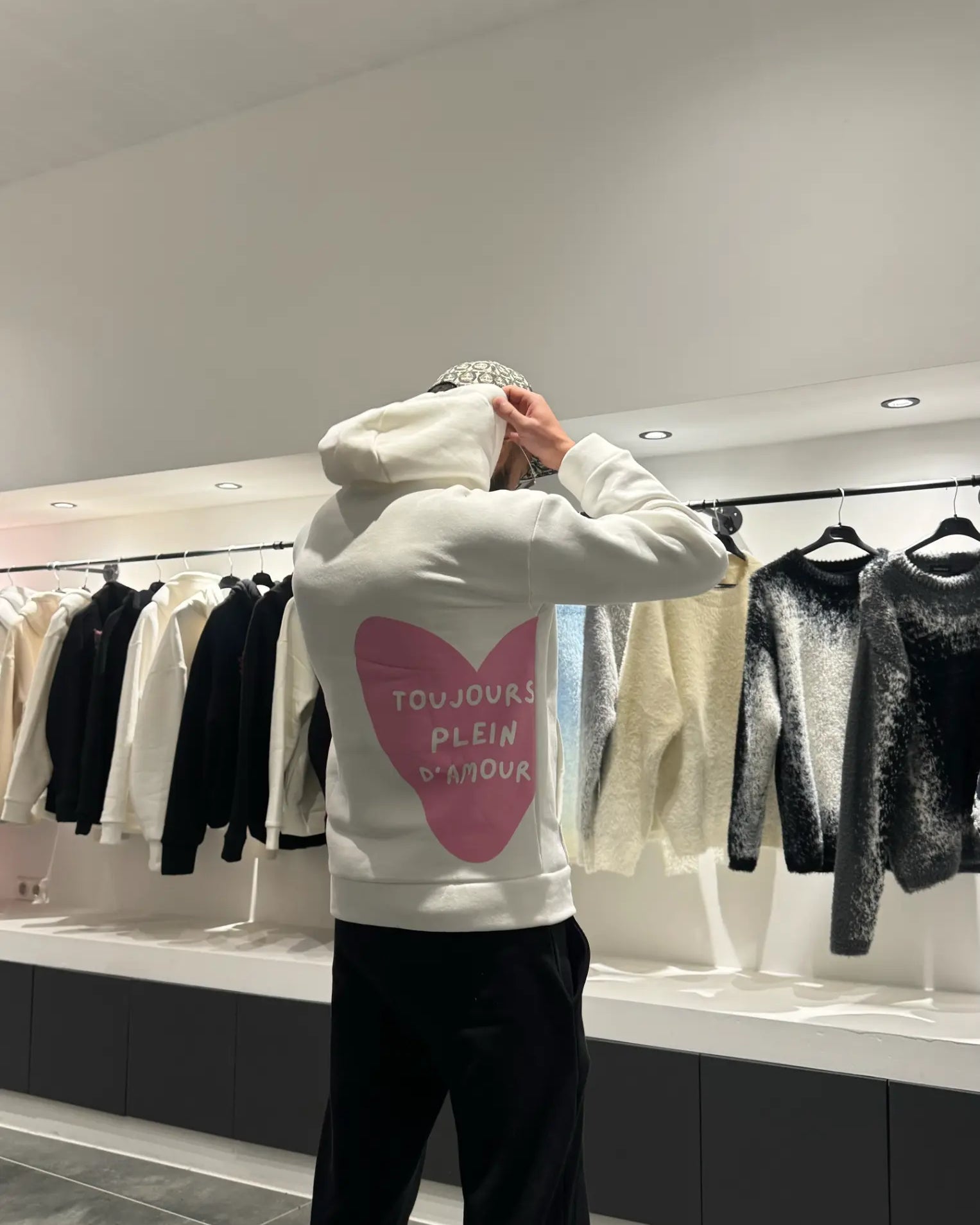Focus sur le message "toujours plein d'amour" écrit en rose au dos du pull blanc ADJ.