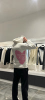 Focus sur le message "toujours plein d'amour" écrit en rose au dos du pull blanc ADJ.