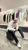 Pose assise mettant en valeur le confort thermique et la texture riche du pull gris.