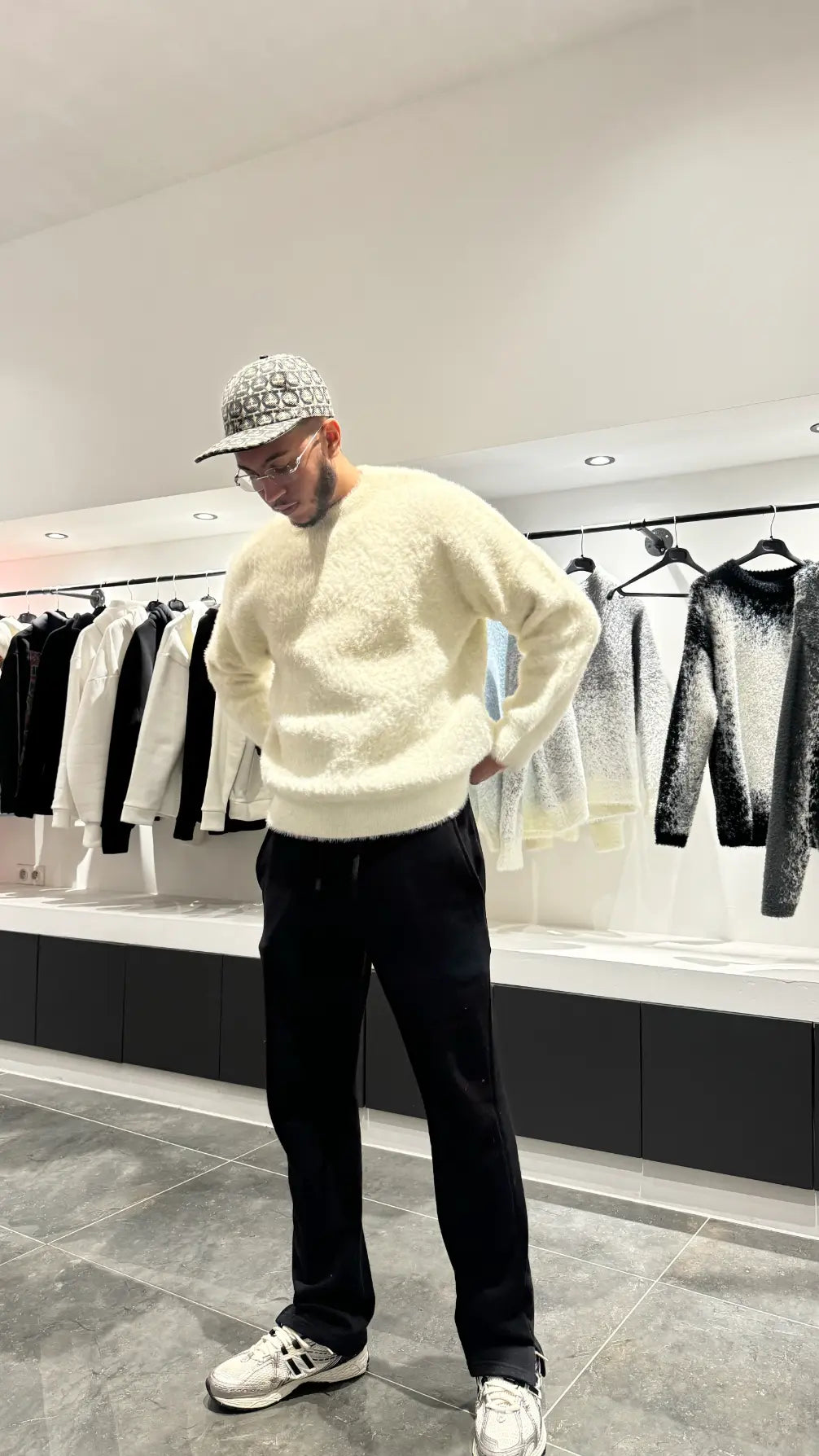 Silhouette élégante du modèle debout avec le pull premium beige au tombé lourd caractéristique.