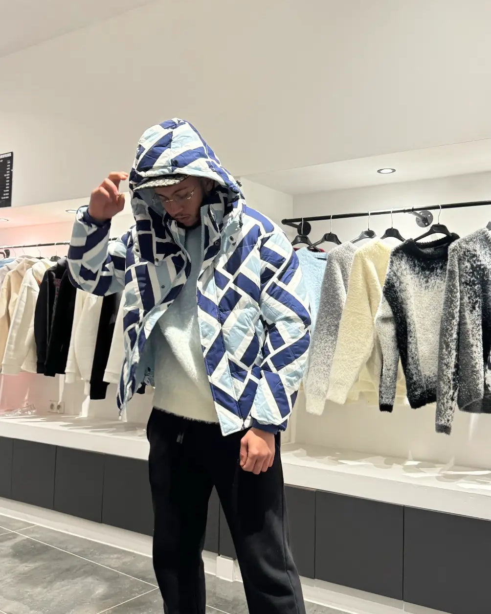 Silhouette complète montrant la doudoune à motif abstrait bleu et blanc avec sa capuche, pour un look street affirmé.