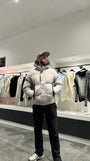 Silhouette complète montrant la doudoune grise monochrome avec sa capuche pour un look d'hiver épuré.