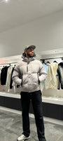 Silhouette complète montrant la doudoune grise monochrome avec sa capuche pour un look d'hiver épuré.