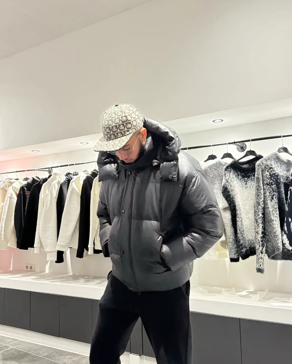 Silhouette complète montrant la doudoune noire brillante avec sa capuche, reflétant la lumière pour un look street haut de gamme.