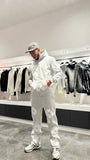 Silhouette complète présentant l'ensemble gris coordonné avec les broderies fleurs blanches bien visibles sur le hoodie et le jogging.