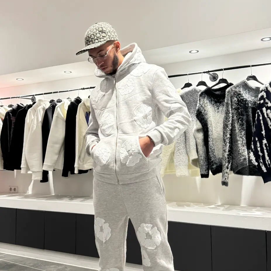 Silhouette complète présentant l'ensemble gris coordonné avec les broderies fleurs blanches bien visibles sur le hoodie et le jogging.