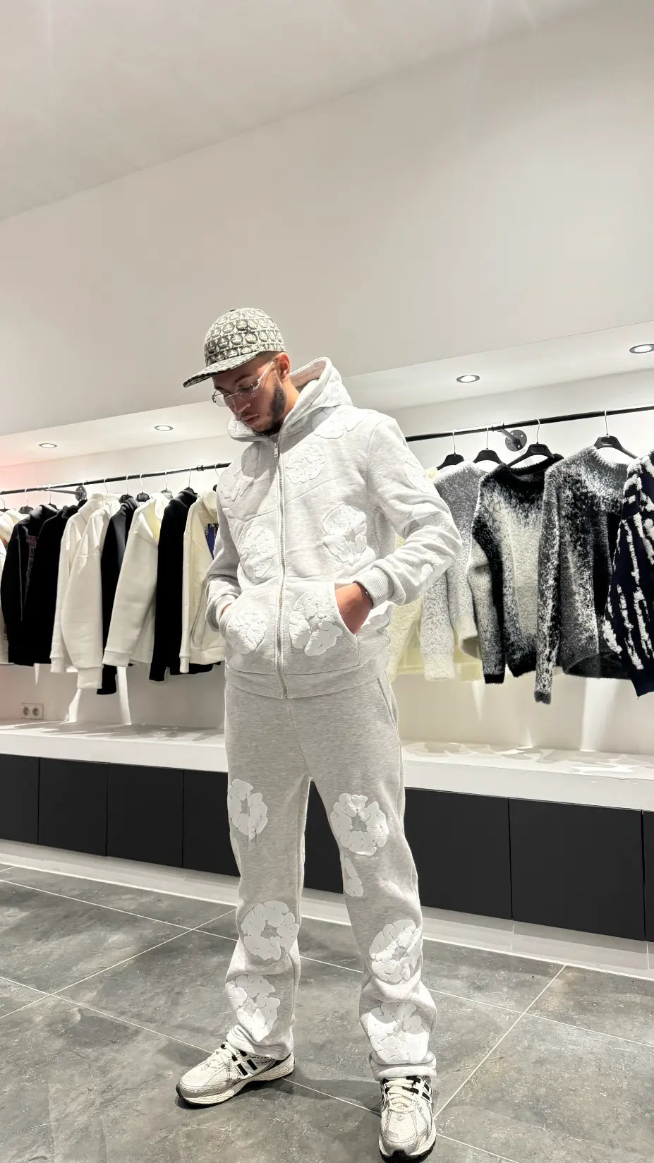 Silhouette complète présentant l'ensemble gris coordonné avec les broderies fleurs blanches bien visibles sur le hoodie et le jogging.