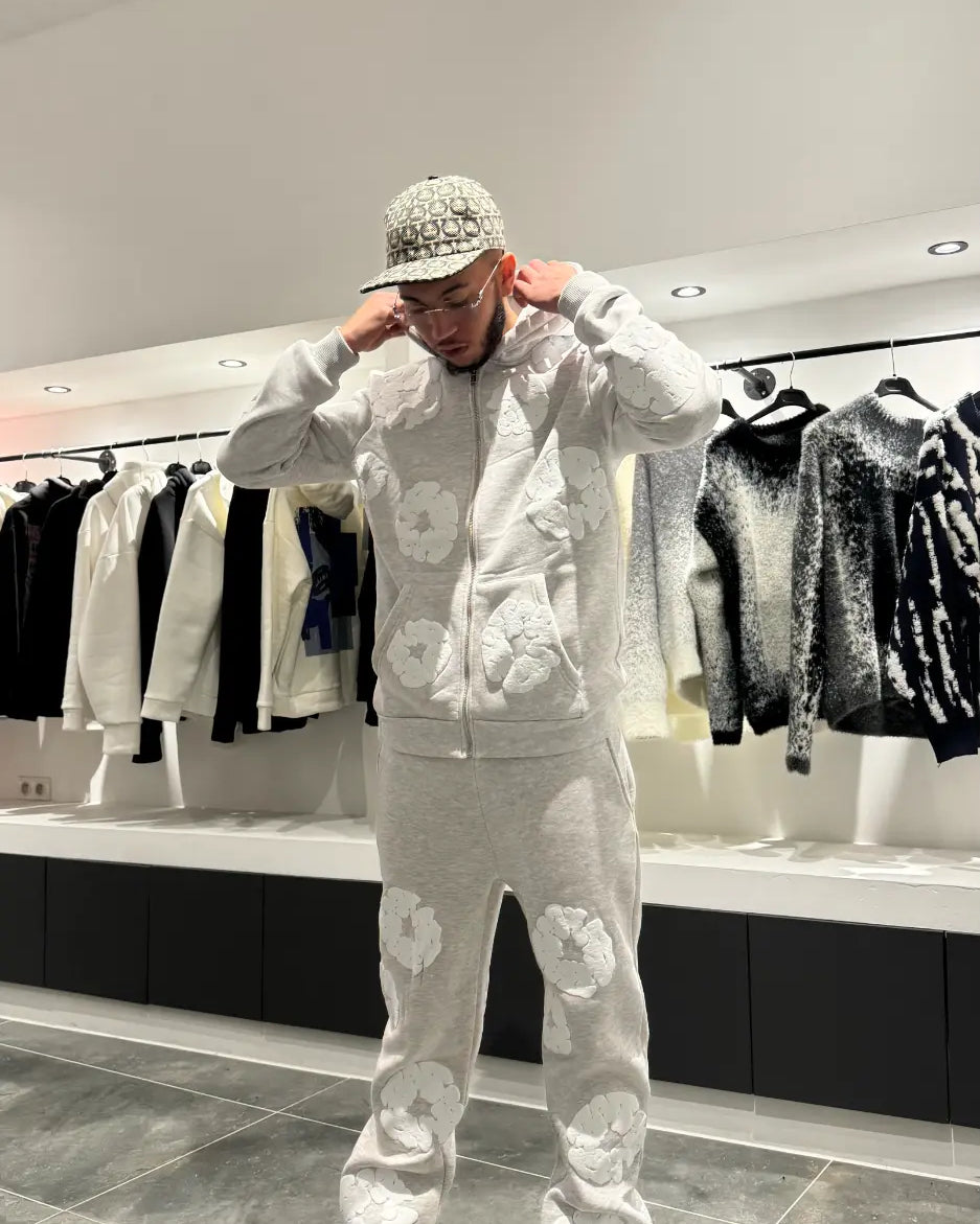 Vue de face montrant la coupe ajustée du pantalon et le hoodie zippé ouvert, révélant un style décontracté.