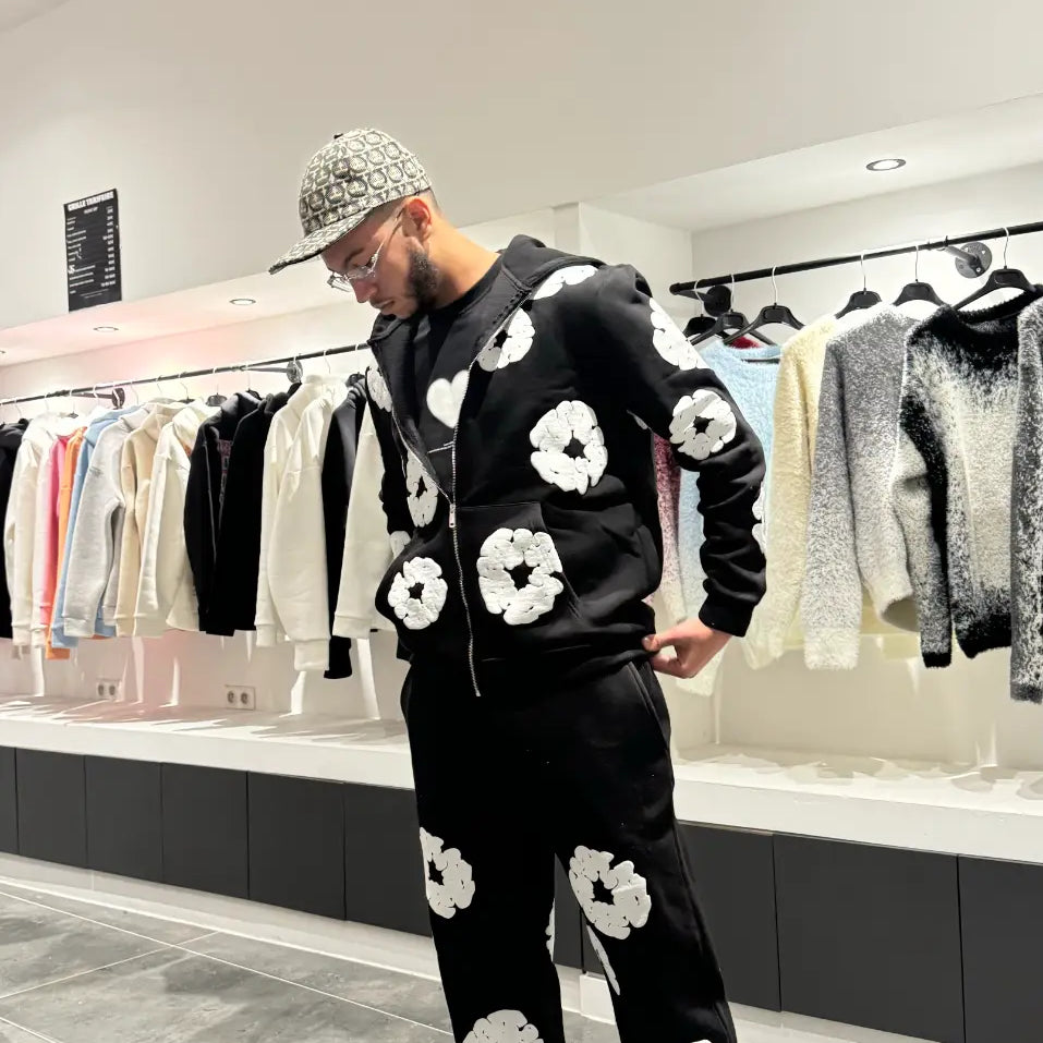 Silhouette complète en ensemble noir avec les fleurs blanches brodées sur le torse et la cuisse.