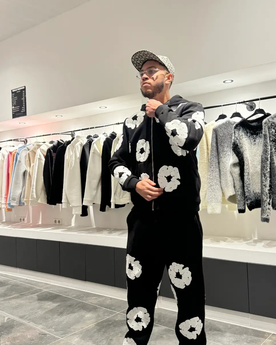 Vue de face de l'ensemble noir montrant le hoodie zippé fermé et la coupe ajustée du jogging.