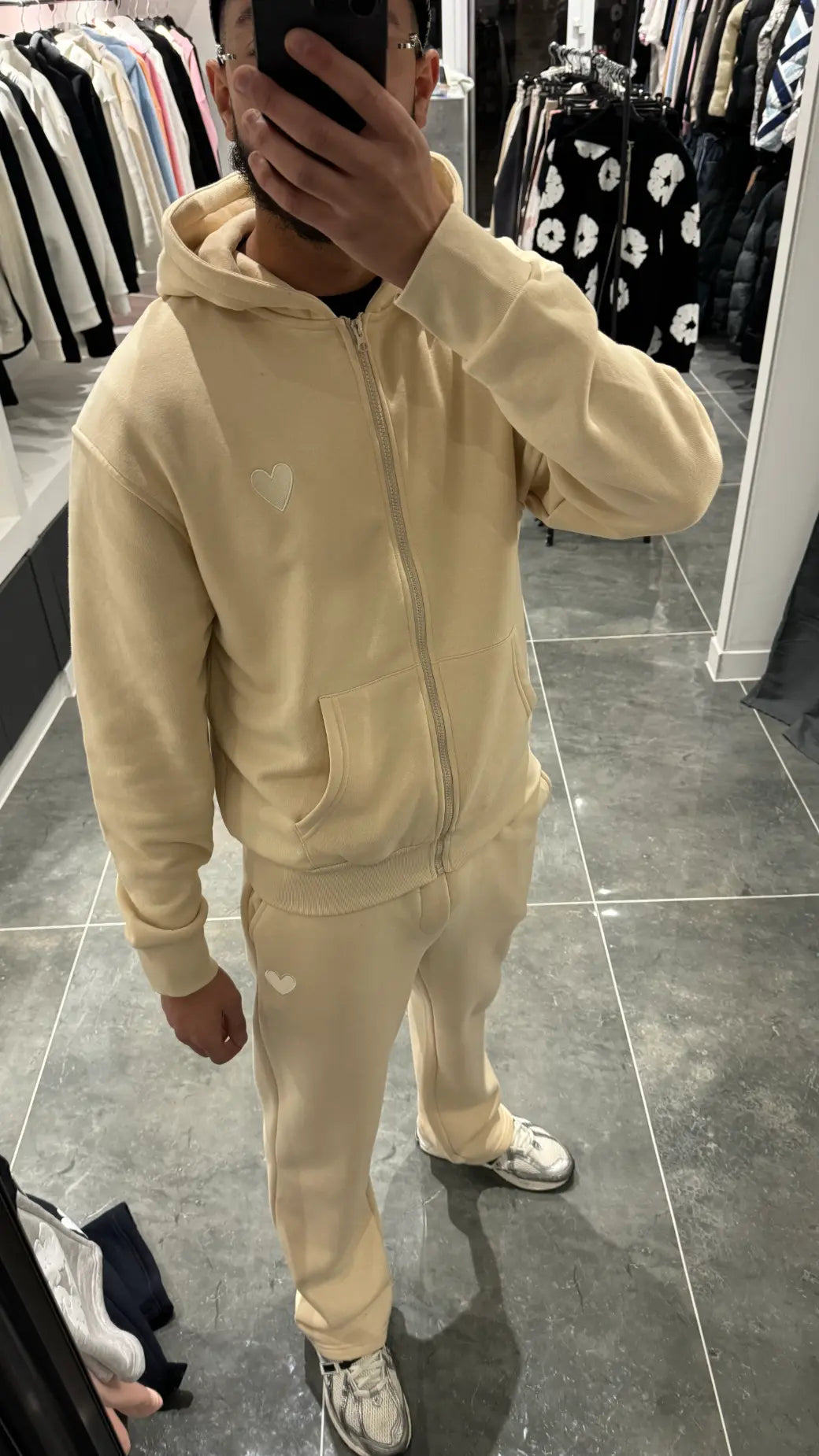 Gros plan sur le logo cœur brodé avec précision sur le tissu jaune premium de la veste.