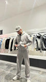 Ensemble complet gris composé d'une veste zippée à capuche et d'un jogging, mettant en avant le petit logo cœur brodé sur la poitrine.