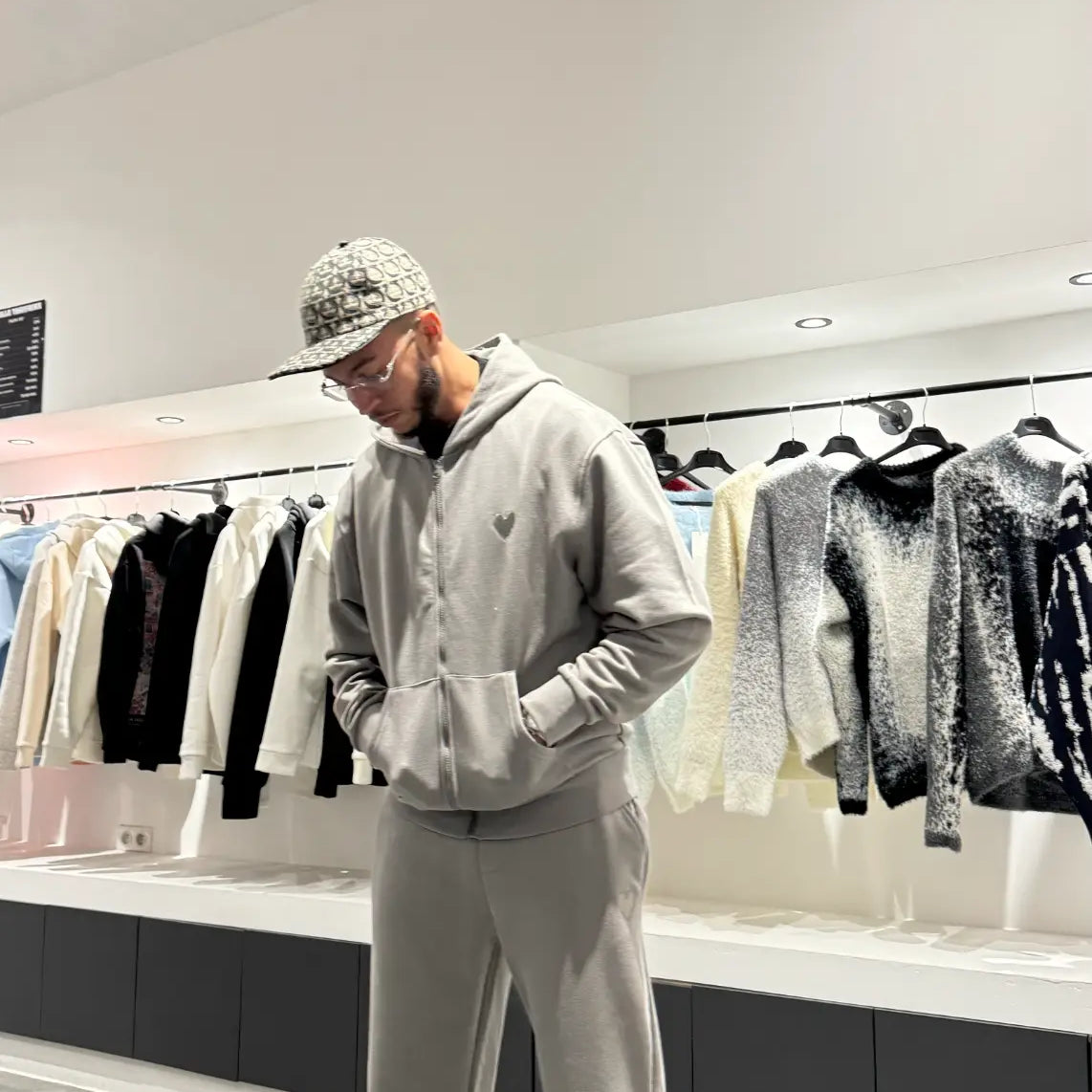 Gros plan sur le détail du logo cœur brodé en relief sur le textile gris chiné, soulignant la qualité des finitions.