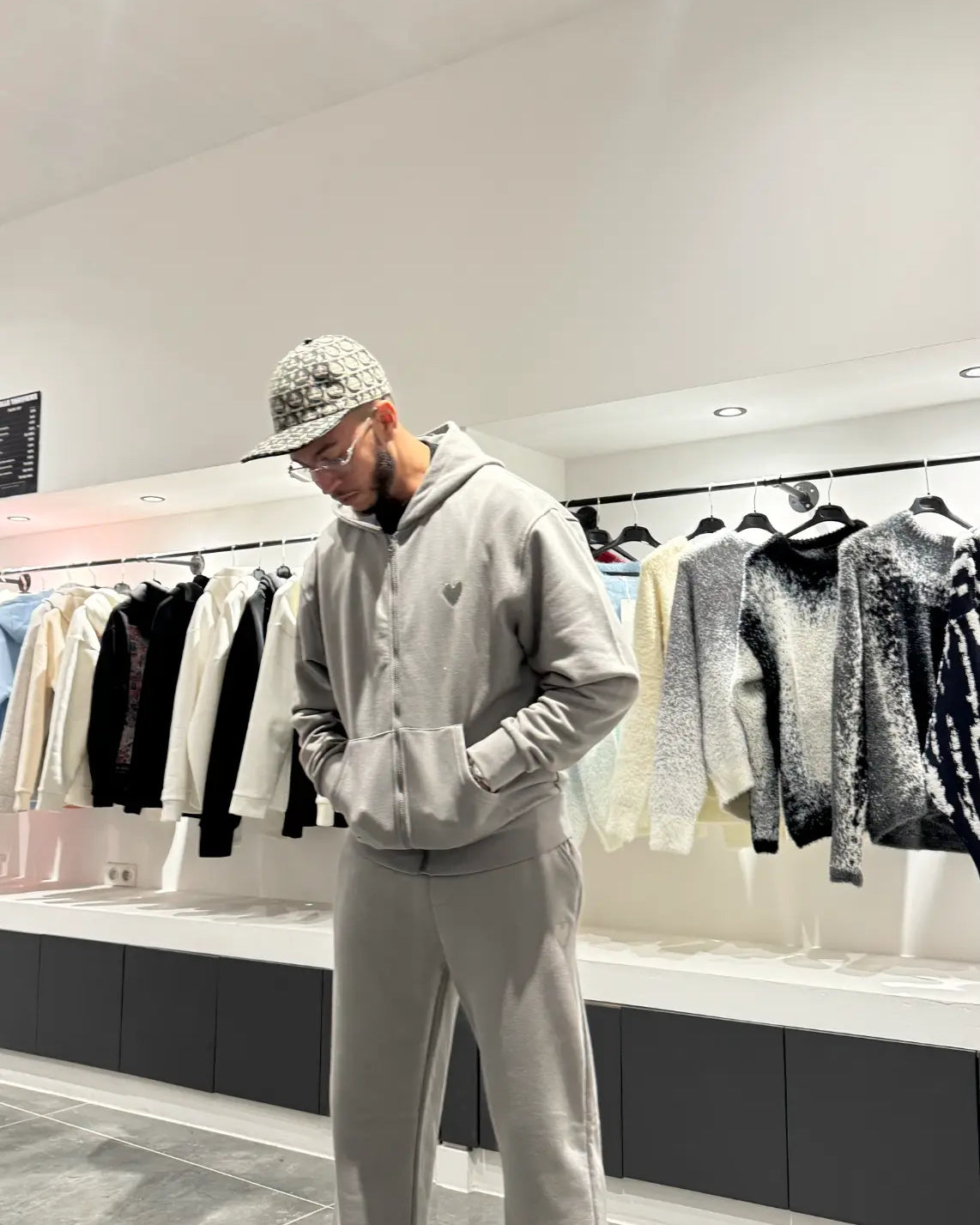 Gros plan sur le détail du logo cœur brodé en relief sur le textile gris chiné, soulignant la qualité des finitions.