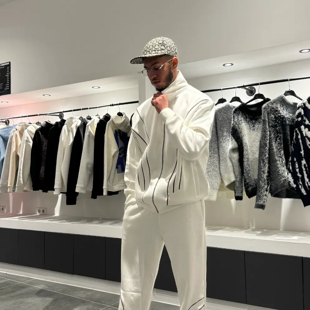 Ensemble blanc oversize composé d'une veste zippée sans capuche et d'un pantalon large, mettant en avant la ligne noire fine sur la poitrine.