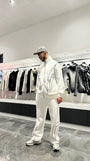 Vue arrière de l'ensemble blanc montrant la coupe oversize-schnitt généreuse et l'absence de détails pour un look minimaliste.