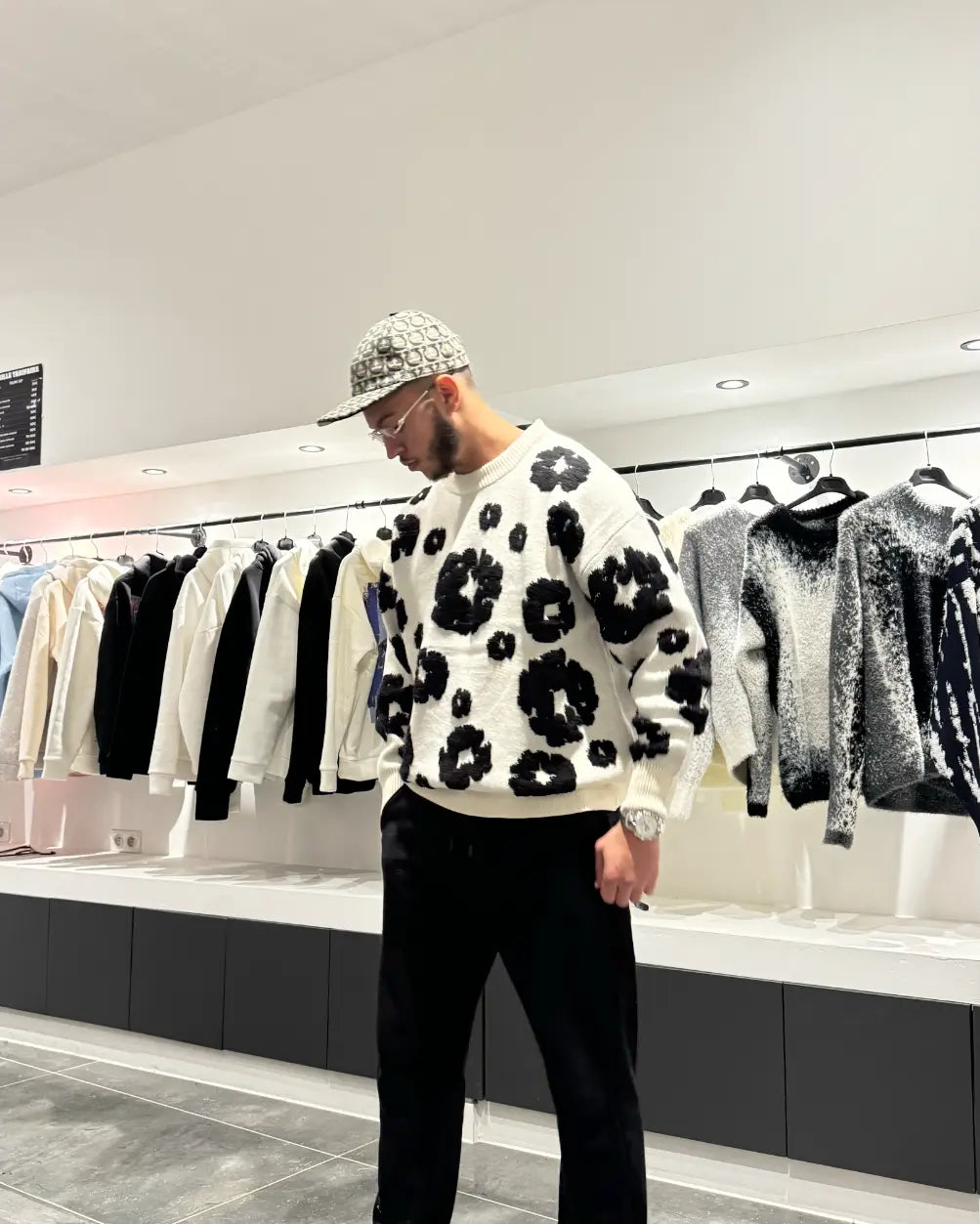 Vue arrière du pull blanc montrant la continuité des motifs floraux noirs brodés, soulignant l'aspect premium.