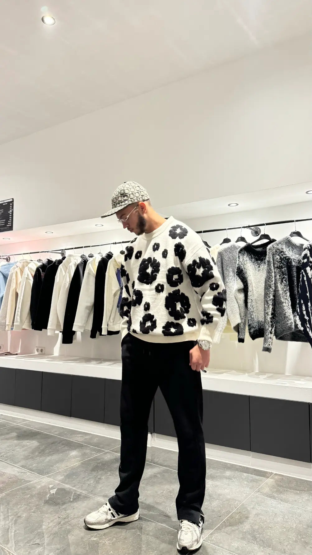 Vue arrière du pull blanc montrant la continuité des motifs floraux noirs brodés, soulignant l'aspect premium.