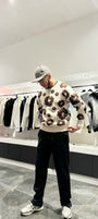 Pull en maille beige oversize avec broderies florales marron sur la poitrine, porté dans une rue de Chambéry.