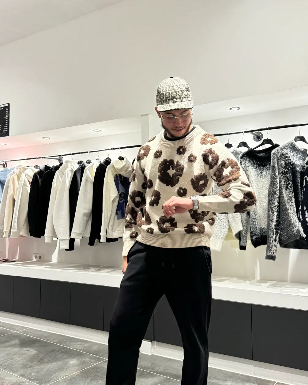 Focus sur les motifs botaniques marron brodés avec précision couvrant l'arrière du pull en maille premium.