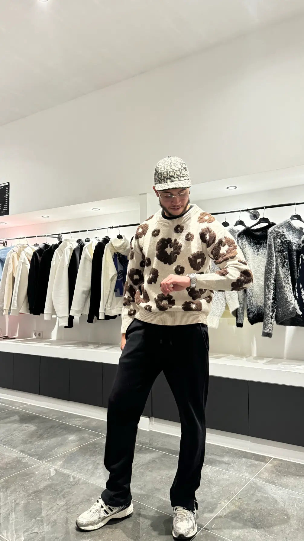 Focus sur les motifs botaniques marron brodés avec précision couvrant l'arrière du pull en maille premium.