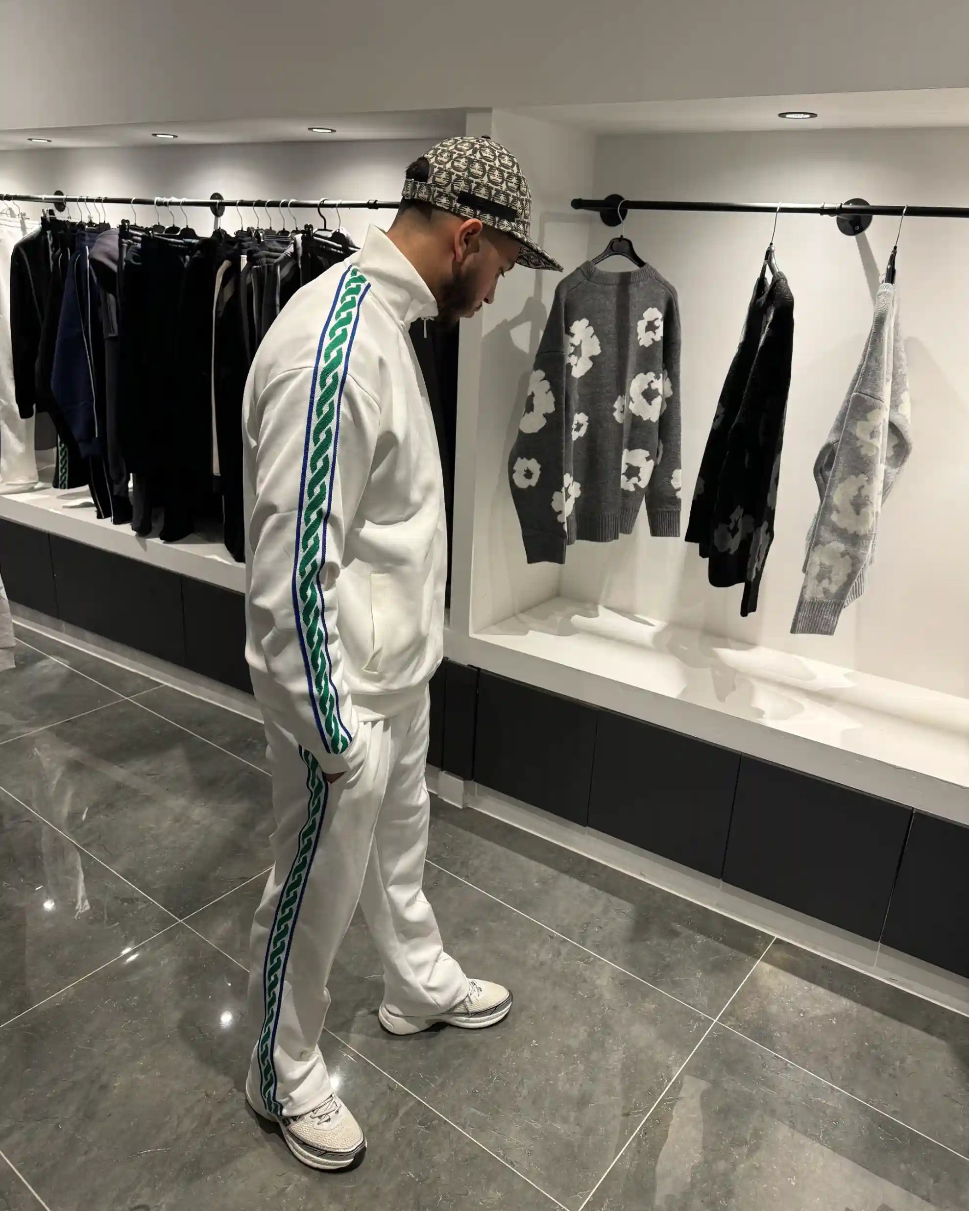 Silhouette complète montrant l'ensemble blanc lumineux et les bandes jacquard vertes le long des membres.