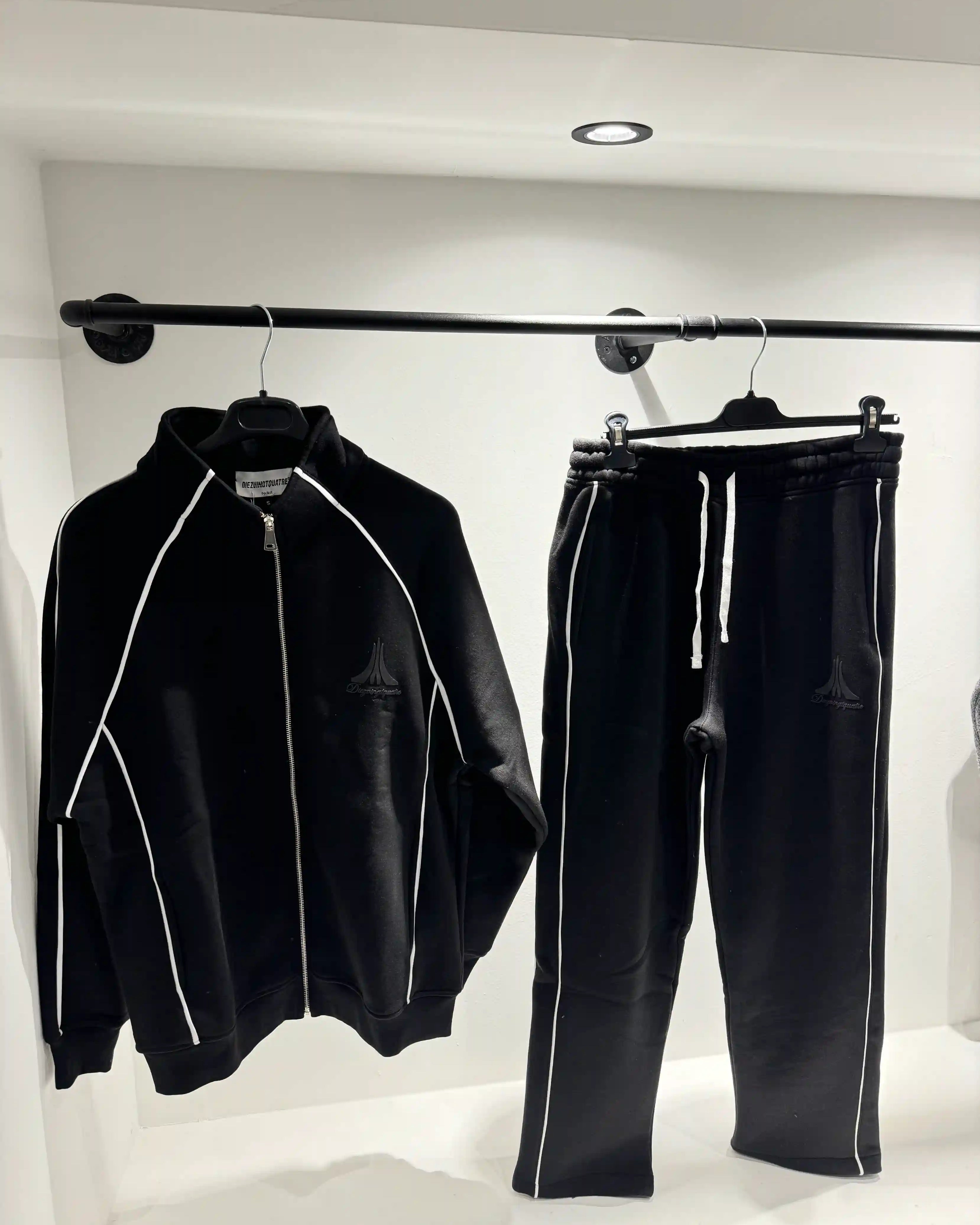 Présentation de l'ensemble noir à lignes blanches sur cintre, illustrant le tombé fluide du vêtement.