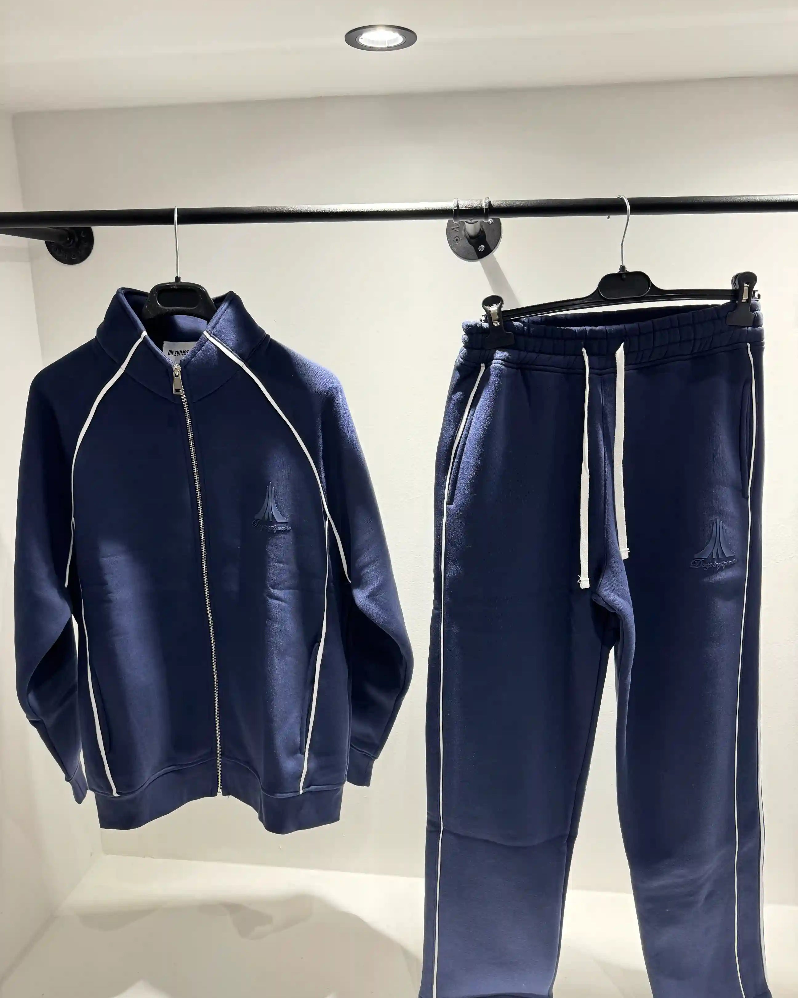 Présentation de l'ensemble bleu foncé sur cintre, illustrant le tombé fluide du vêtement et la clarté des lignes.