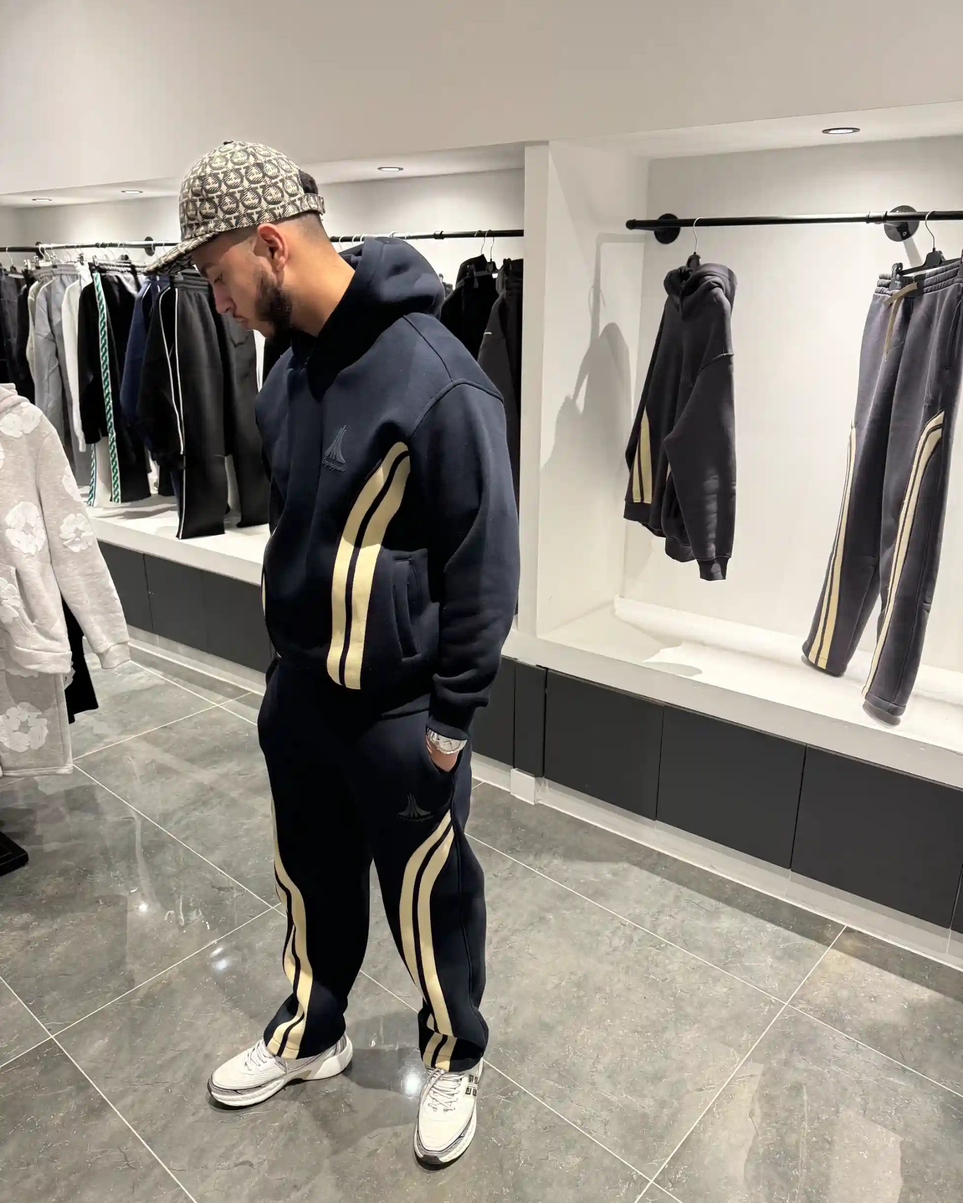 Silhouette complète présentant l'ensemble bleu foncé et l'impact visuel des larges bandes beiges latérales.